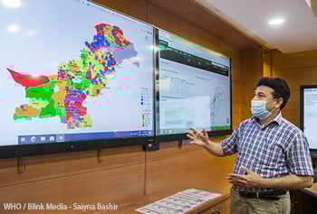 Technical officer for information management shows data on Pakistan's COVID-19 response in an operations room.