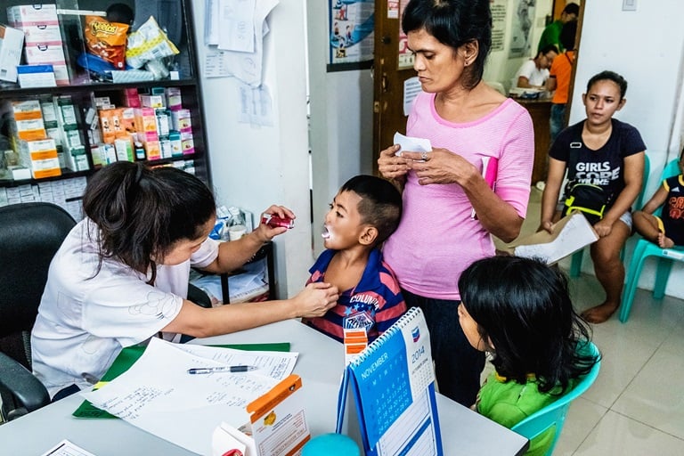 A mother brings her children for check-up and vaccination at the Corazon Aquino Health Center in Baseco Compound, Tondo, Manila. All services are free at the health center.